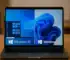 Laptop med jämförelse mellan Windows 10 och Windows 11 på skärmen.